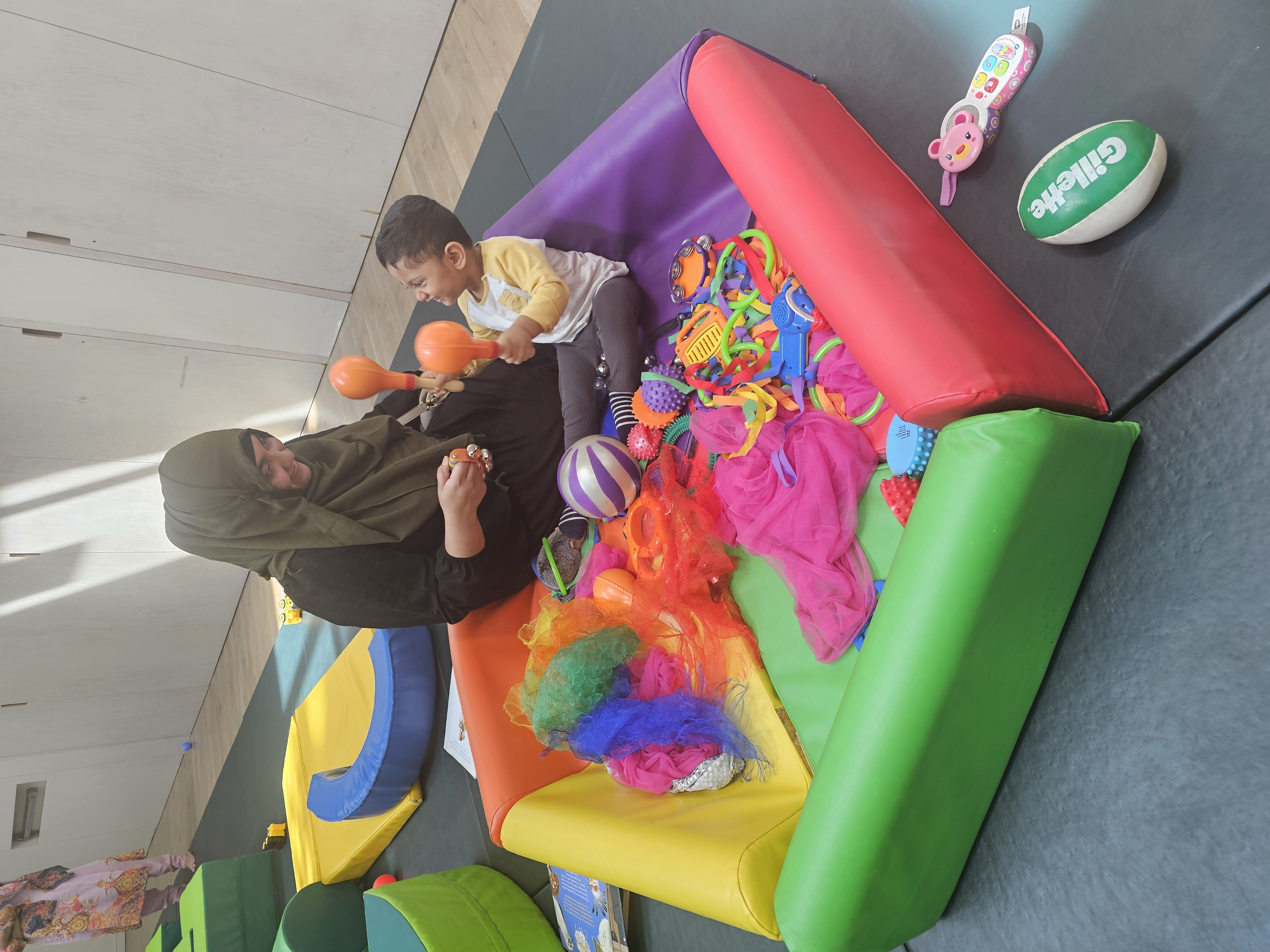 Mother and toddler playing with toys in baby gym