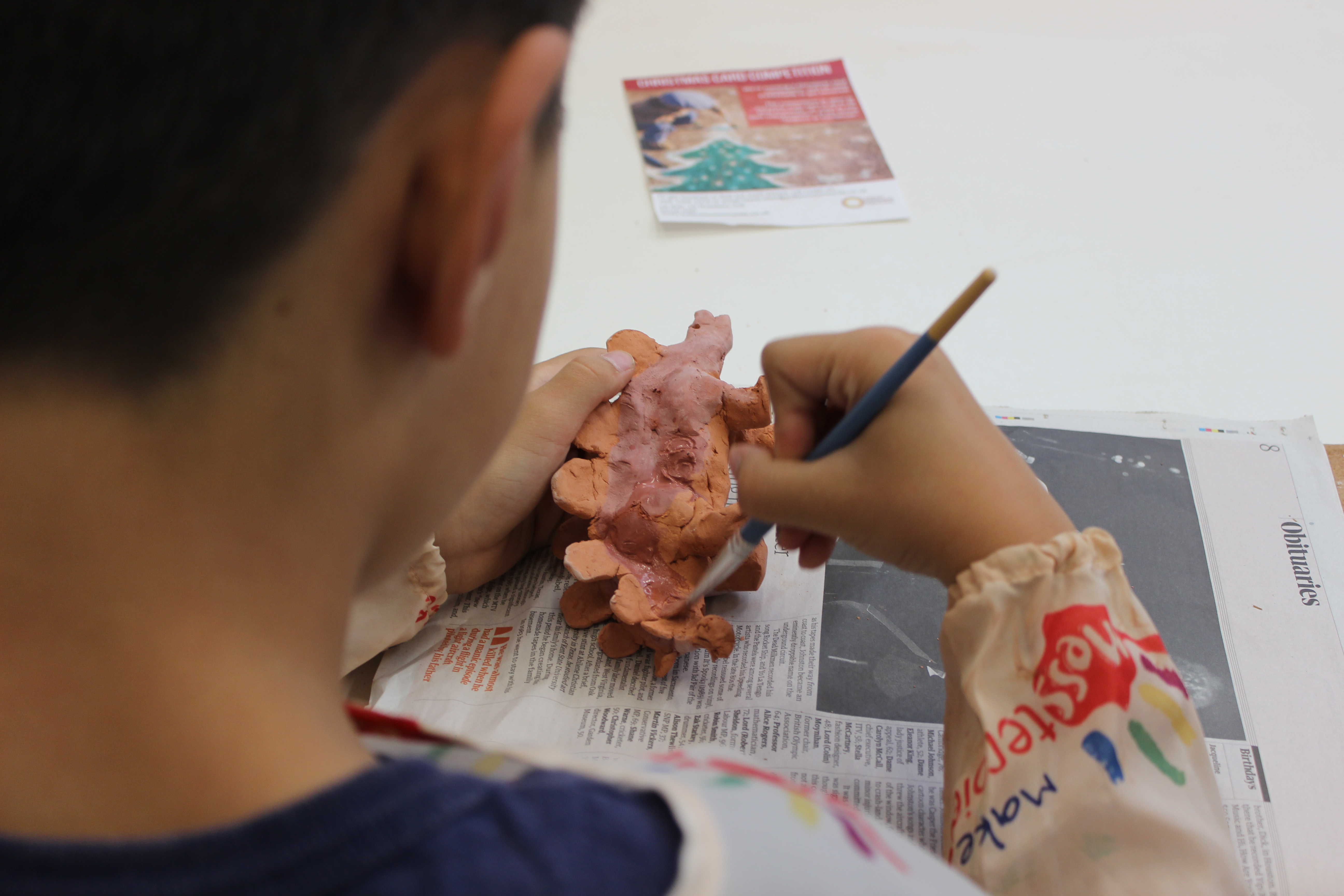 Image of a boy painting a ceramic dinosaur with a paintbrush