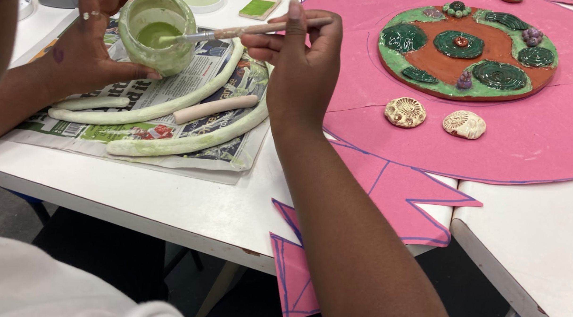 A close up image of hands painting a ceramic sculpture