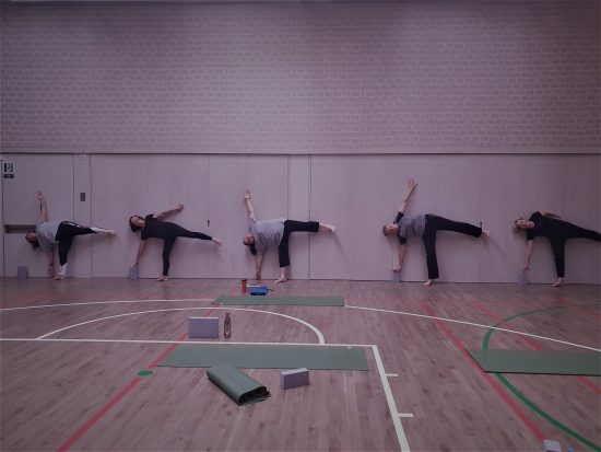 A group of women stretching with their left arms and legs off the floor 