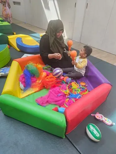 Mother and toddler playing with toys in baby gym