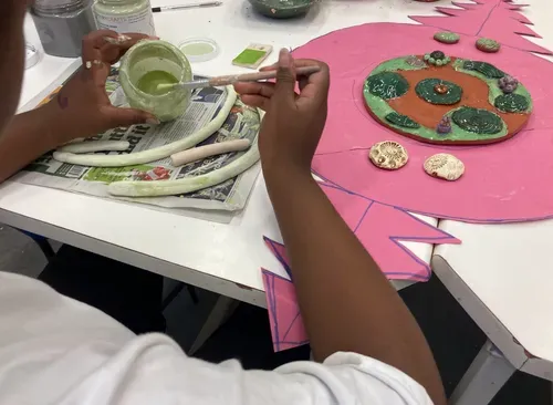 A young person painting their pottery