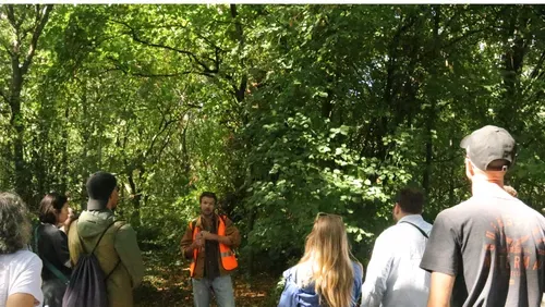 A group listening to a talk in a wooded area.