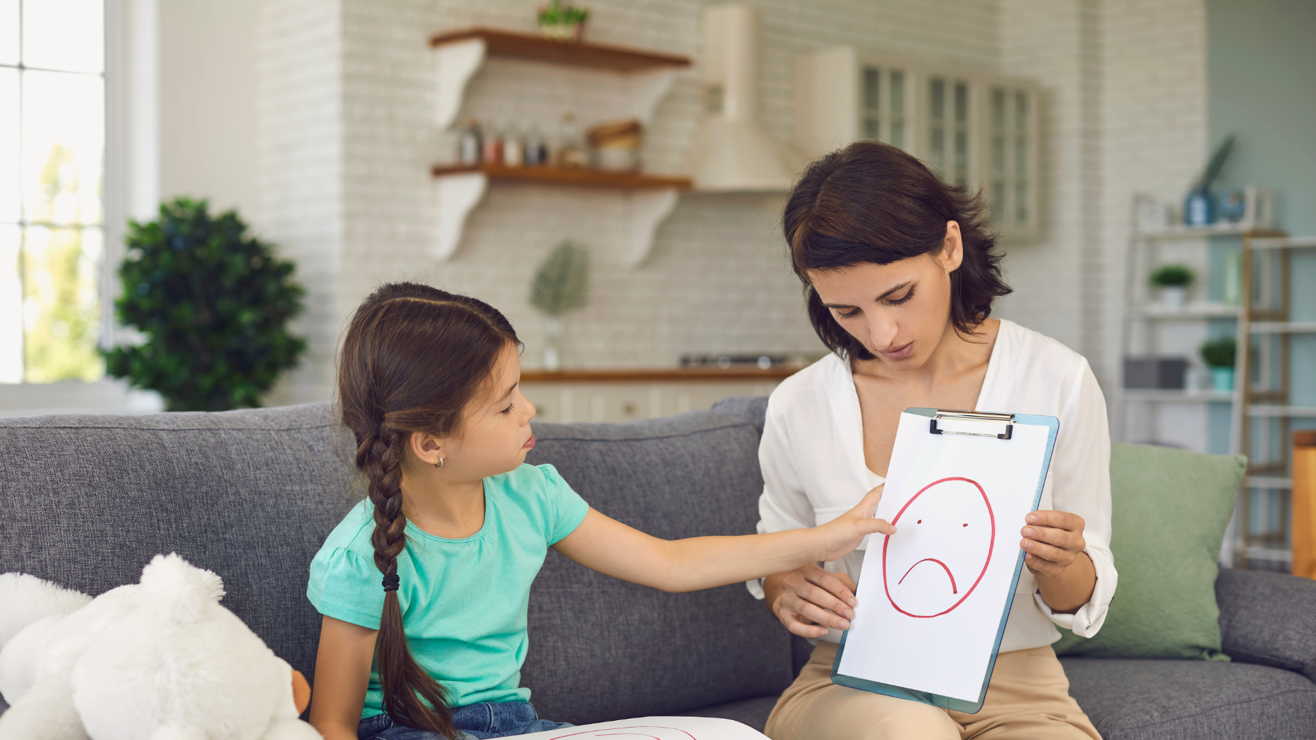 Child pointing to a sad face on a clip board
