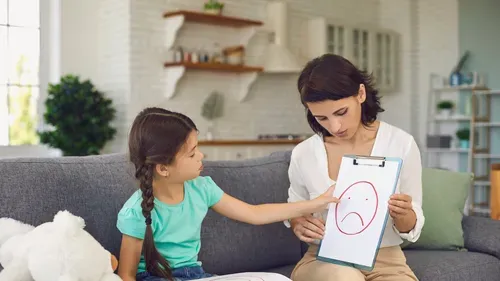 Child pointing to a sad face on a clip board
