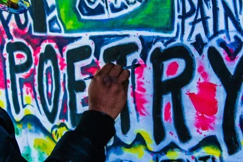 Someone painting the word 'poetry' onto a wall.