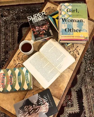 a collection of books with a hot drink on a coffee table on a patterned rug