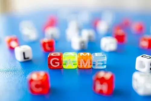 dice on a blue table, the dice in the middle have letters on them spelling 'game'