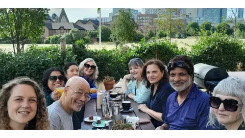 people from the walking group sitting around the breakfast table outside, park in the background