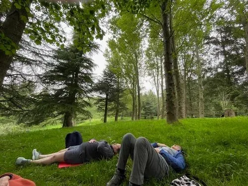 image of two women lying on ground beneath a canopy of trees. 