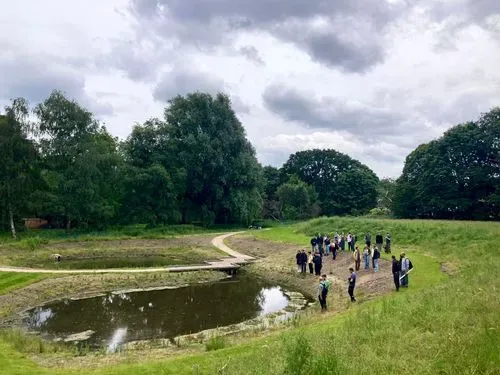 People stand on waters edge at the ponds