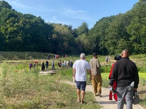 People walk across wetlands on a sunny clear sky day