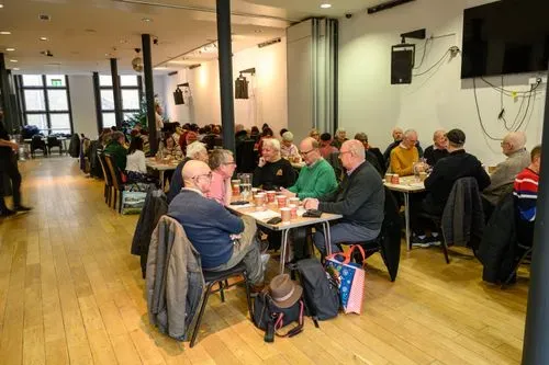 Room with large rectangular table and a group of individual sharing a meal