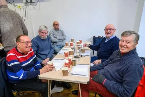 Six people sitting around a rectangular table sharing conversation and food