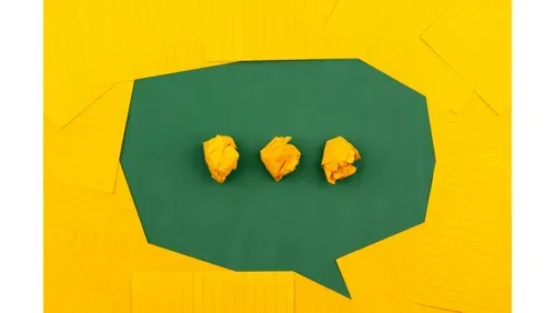 dark green speech bubble cut out in paper. It sits on a bright yellow background.