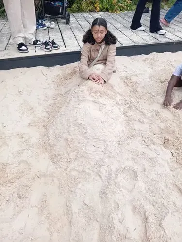 A young person buried in sand at a fun day out at Kew Gardens!