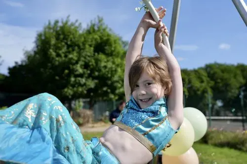 A young girl smiling on an outdoor aerial hoop