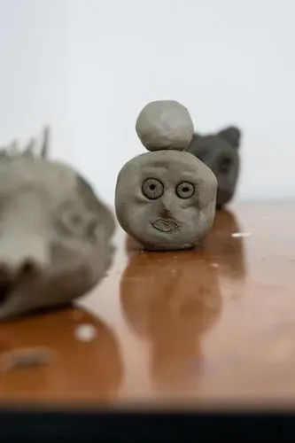 Self-portrait heads made from clay sitting on a brown table.