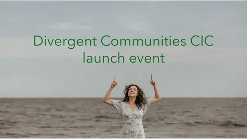 Rosie Brighty, a white woman with dark curly hair, smiling and pointing upwards at green text above her that reads “Divergent Communities CIC launch event”. The sea is in the background.
