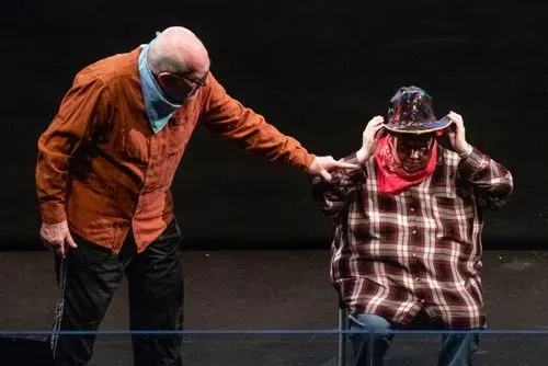 A man stands reaching out to a seated women wearing a cowboy hat