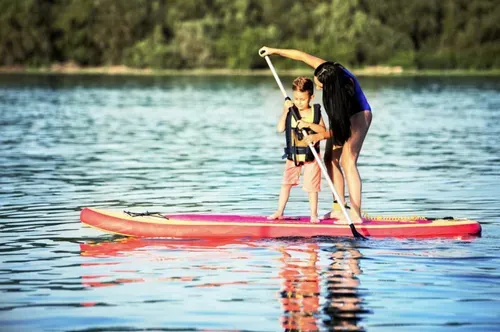 woman helping child on paddleboard