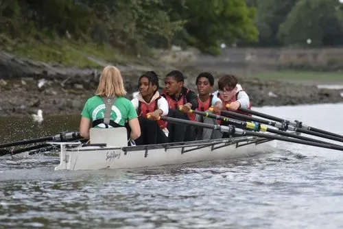4 young people rowing in a boat on the Thames in London
