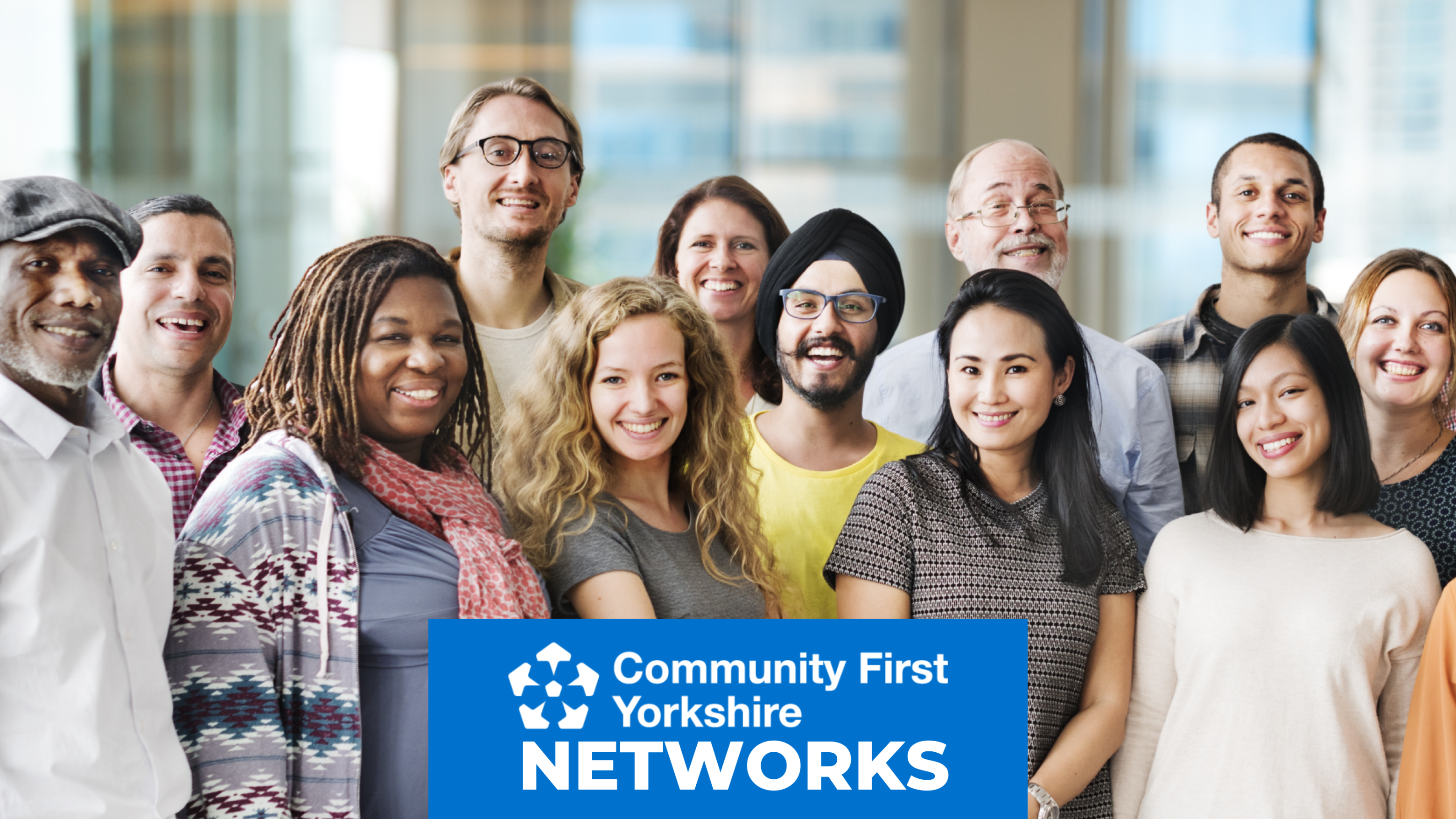 Group of people standing together indoors with a blue banner that reads “Community First Yorkshire Networks.”