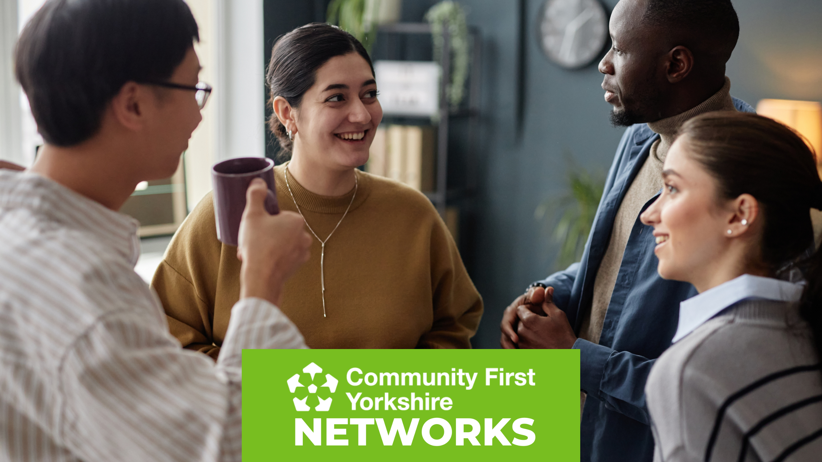 People standing and talking in a casual indoor setting with a green banner at the bottom that reads “Community First Yorkshire Networks.”