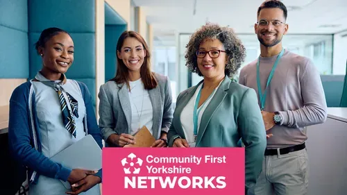 Four people standing in an office setting, wearing business attire and lanyards, holding folders and notebooks. Pink banner reads “Community First Yorkshire Networks.”