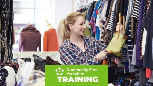 Person browsing clothing racks in a shop, holding a green handbag among various garments. Green banner reads “Community First Yorkshire TRAINING.”