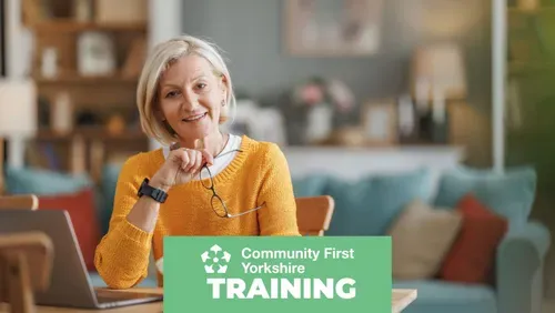 Woman in a home setting working on her laptop smiling to camera with the Community First Yorkshire logo and the word training on a green content block