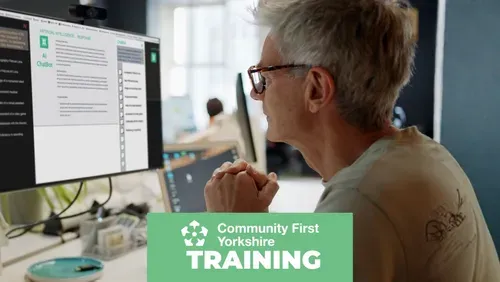 Older person look at computer screen in an office environment with Community First Yorkshire logo and the word training on a green colour block