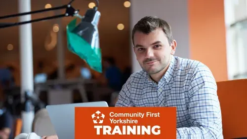 Person working on a laptop in a modern office or co-working space, with Community First Yorkshire Training branding displayed across the bottom of the image.