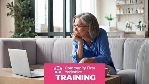 older woman sitting on her sofa working on her laptop with Community First Yorkshire logo and word training on a pink colour content block