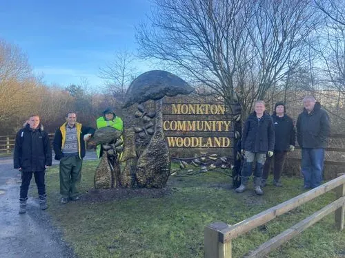 Our team of volunteers standing with our new 8ft tall sculpture, featuring beautiful huge mushrooms, butterflies and birds to capture what the site offers.