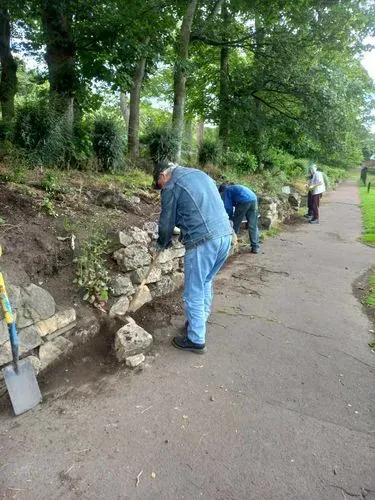 Our team of volunteers clearing mud and debris from around benches and the stone wall along the old bowling greens.