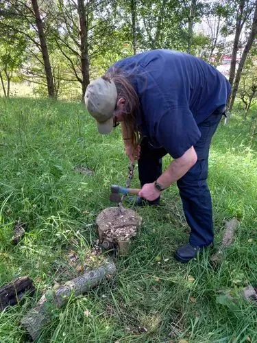 One of our volunteers using a small hand axe and sharpening technique  to carve a point on the end of a branch to make wooden stakes to use as fence posts.