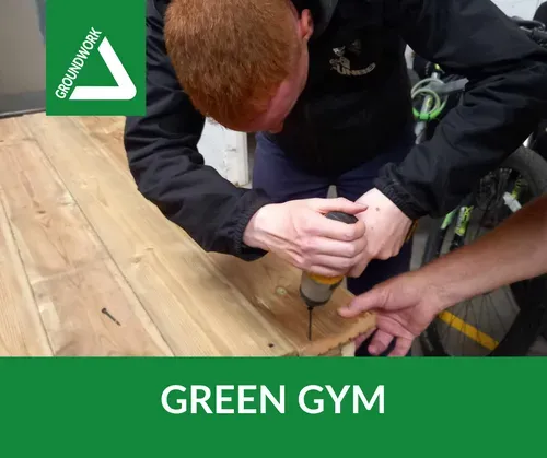 One of our volunteers using a drill to assemble tables made from decking boards during one of our Green Gym sessions at Jarrow Hall.