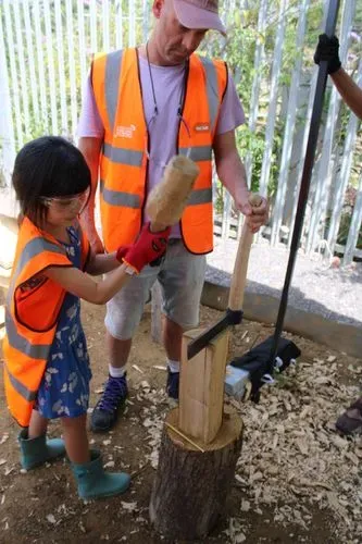  A child uses a mallet to hit a froe and split a log