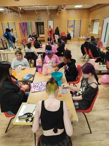Young people are gathered around a table doing some craft activities